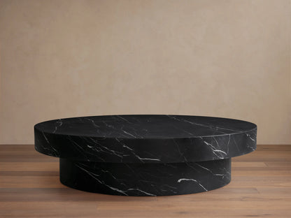 Cinzia Stone Round Coffee Table in black marble with white veining, featuring a low-profile, plinth-style base on a wood floor.