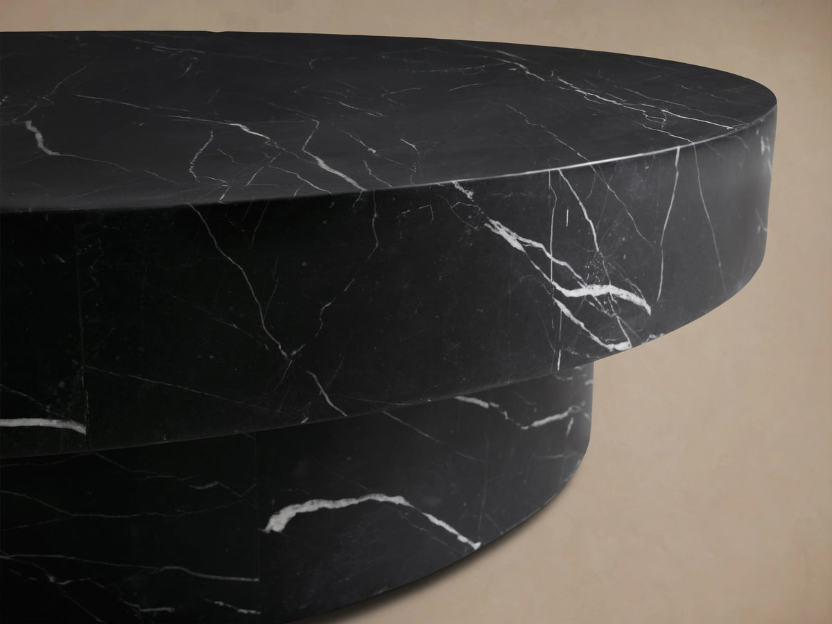 Front view of the black marble Cinzia Stone Round Coffee Table with white veining and a solid plinth base.