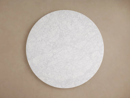 Cinzia Stone Round Coffee Table with a circular marble top and plinth-style base. Light gray tones, natural veining, on wooden floor.