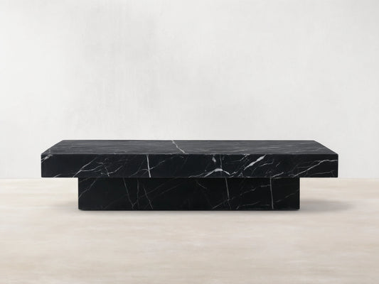 Cinzia Stone Coffee Table in black marble with white veining, low-profile, rectangular top, plinth-style base, on wooden floor.