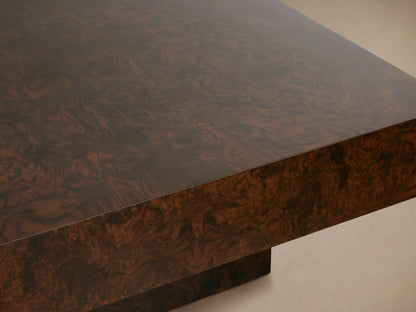 Close-up of Cinzia Burl Coffee Table, dark brown walnut burl wood, intricate swirling grain, reflective top, low plinth base.