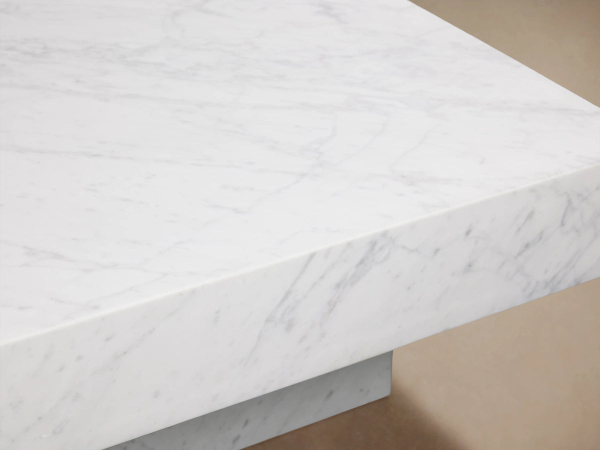 Cinzia Stone Coffee Table with smooth white marble surface and subtle grey veining, featuring a low-profile, plinth-style base.