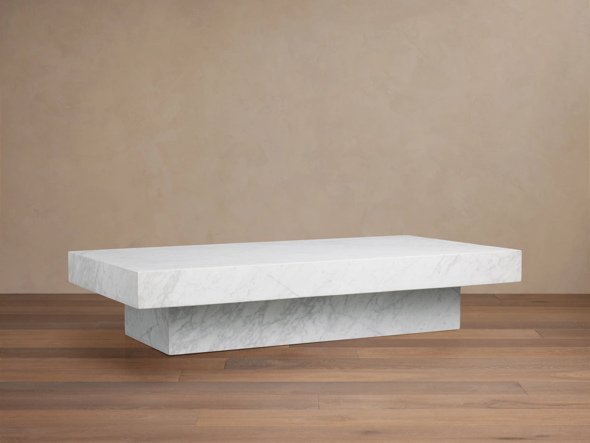 Cinzia Stone Coffee Table with a low-profile rectangular silhouette made of white marble, featuring subtle veining, on a plinth-style base.