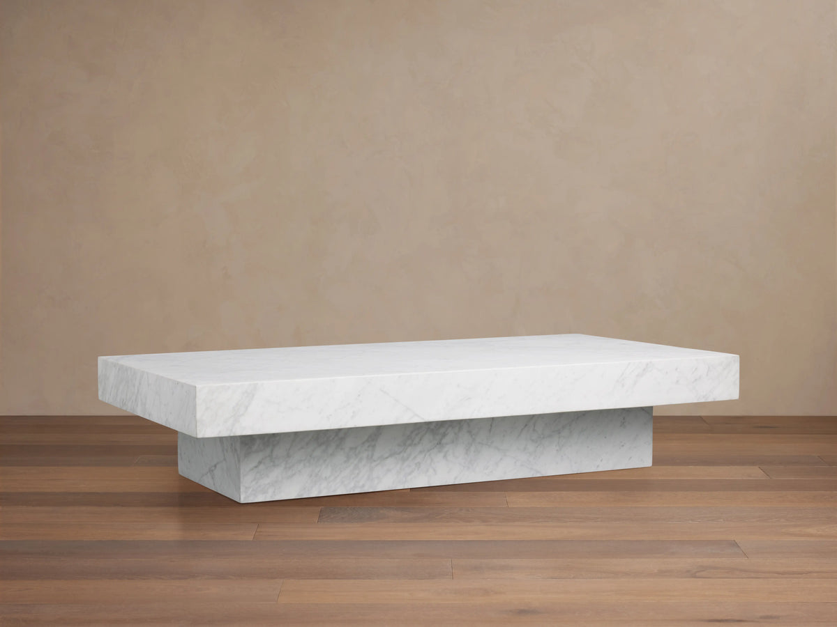 Cinzia Stone Coffee Table with a rectangular marble top featuring natural veining against a warm beige background.
