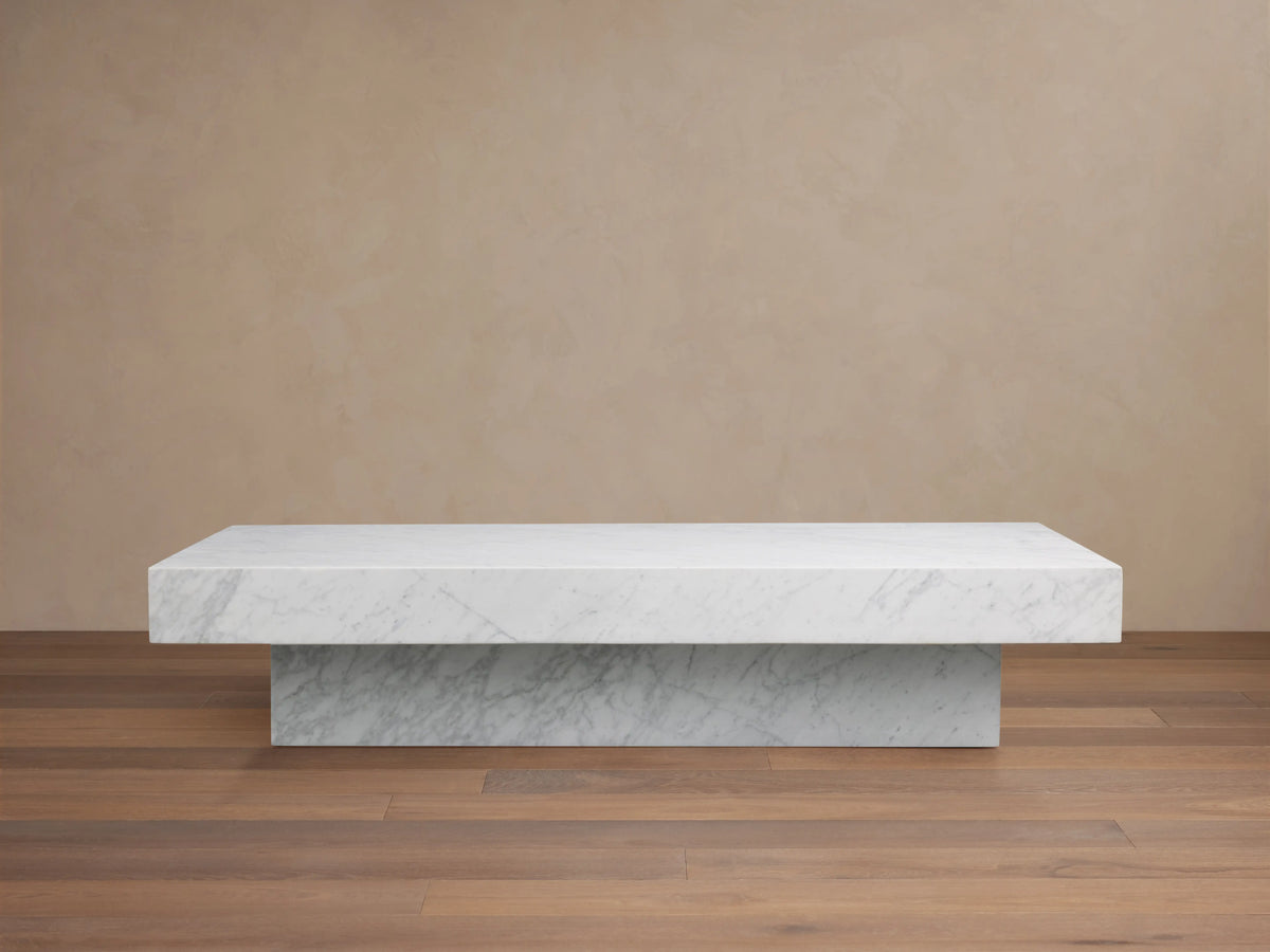 Cinzia Stone Coffee Table with natural marble finish, rectangular shape, low-profile silhouette, and plinth-style base on wooden floor.