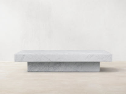 Cinzia Stone Coffee Table with a low-profile rectangular design, crafted from white marble, featuring subtle veining, on a wooden floor.