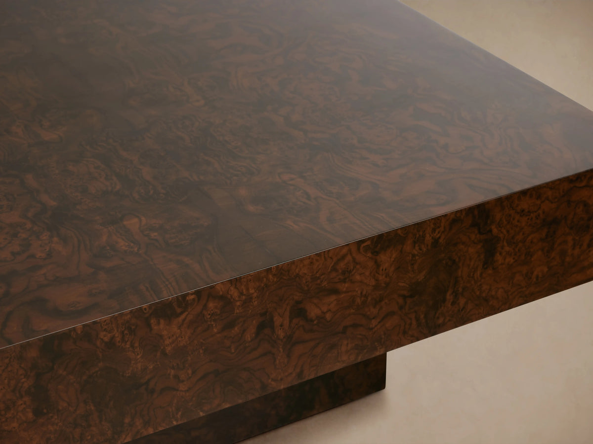Cinzia Burl Coffee Table with a rectangular walnut burl wood veneer top and a plinth-style base on a wooden floor.
