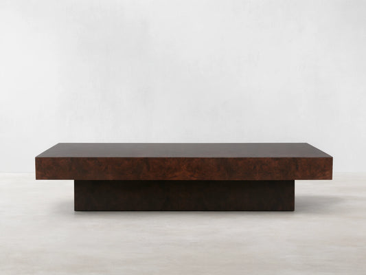 Cinzia Burl Coffee Table in walnut burl wood veneer with a low-profile, rectangular design on a plinth-style base, displayed on wood flooring.