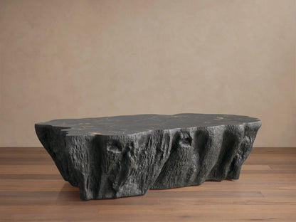 Clayhill Coffee Table with a dark petrified wood surface. The table has an irregular, sculptural form with textured sides, on a wooden floor.