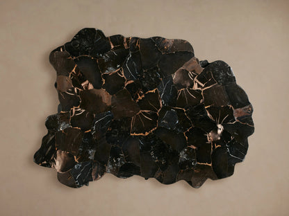 Clayhill Coffee Table in dark petrified wood with an irregular, organic shape, polished surface, on a wooden floor.