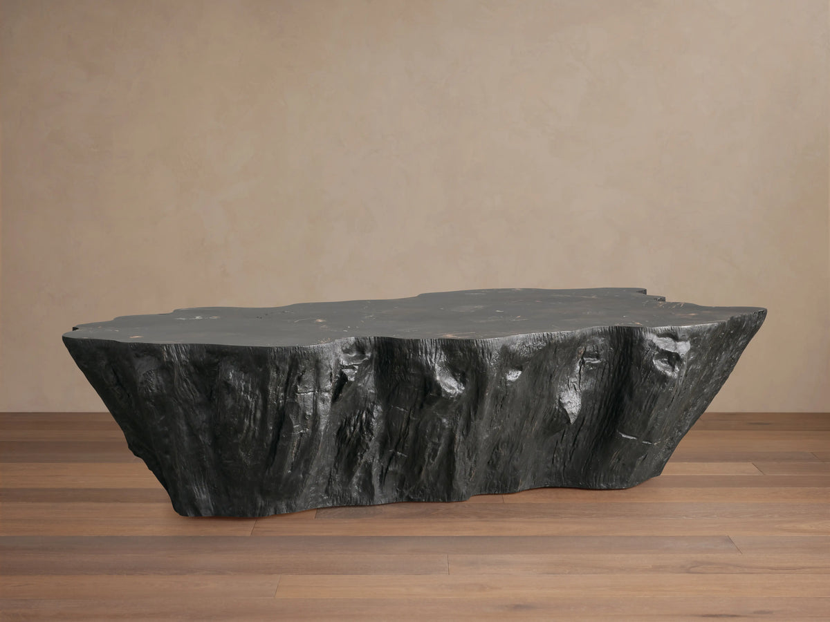 Clayhill Coffee Table made from dark petrified wood with organic texture, irregular edges, and a polished surface on a wooden floor.