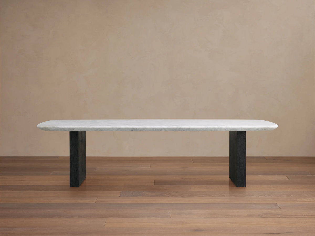 Saint Germain Stone Top Coffee Table with white marble top and dark wooden base, set on wood floor against beige wall.