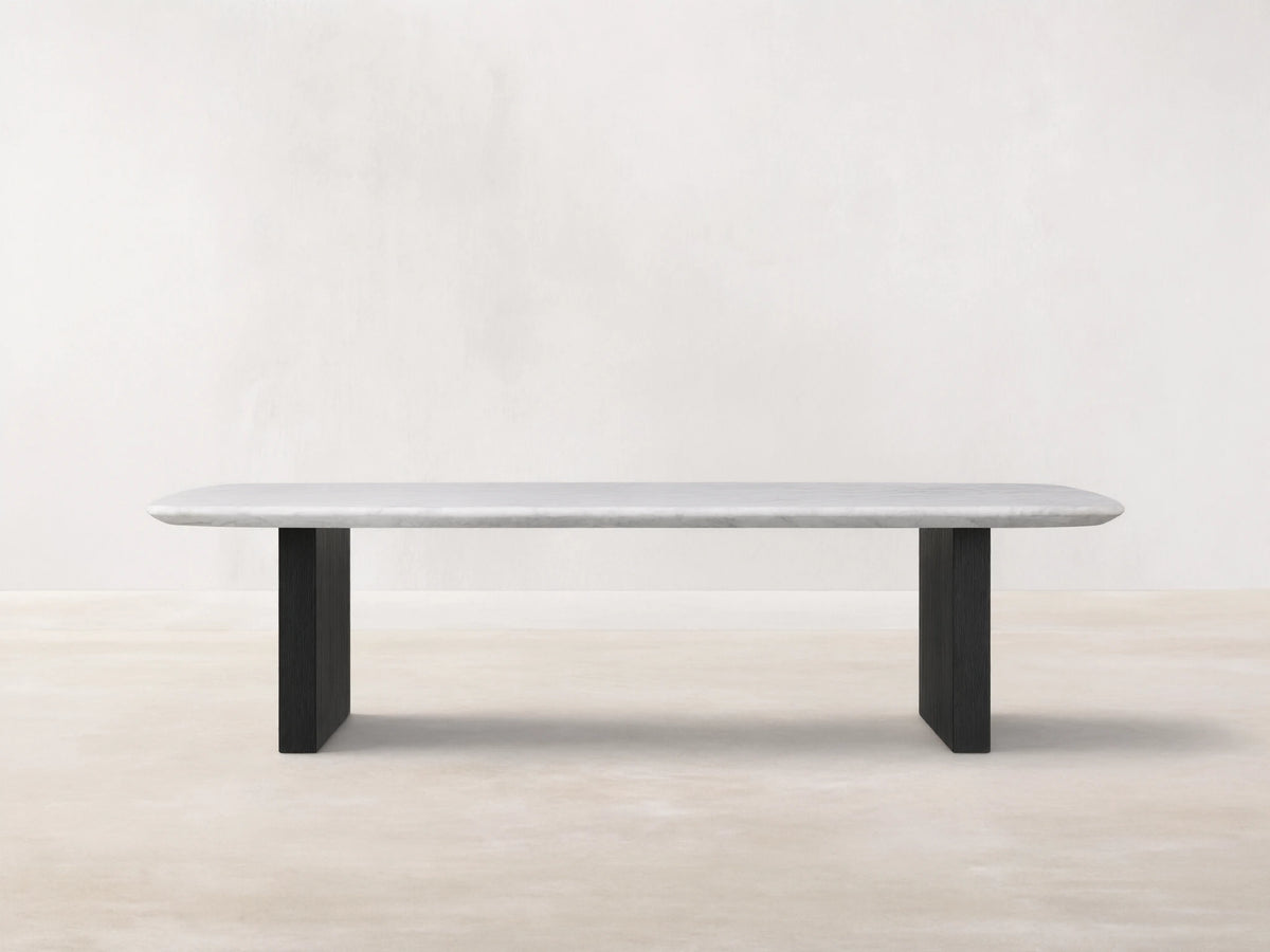 Saint Germain Stone Top Coffee Table with white marble top and dark wooden base, set on wood floor against beige wall.