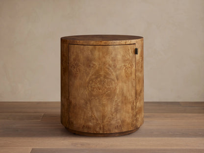 Corey Storage End Table: Cylindrical light brown mappa burl wood cabinet with swirling patterns, dark handle, on wood floor.