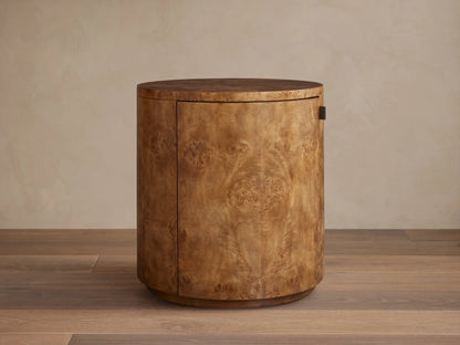 Cylindrical Corey Storage End Table with natural mappa burl wood finish, next to a beige sectional sofa.
