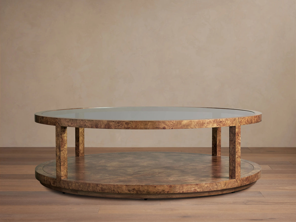 Corey Round Coffee Table in swirling mappa burl wood, featuring a glossy top, round lower shelf, and cylindrical supports.