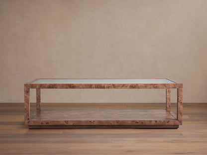 Corey Coffee Table with a rectangular shape, mappa burl wood finish, and open design. It has a top and lower surface in a light brown room setting.