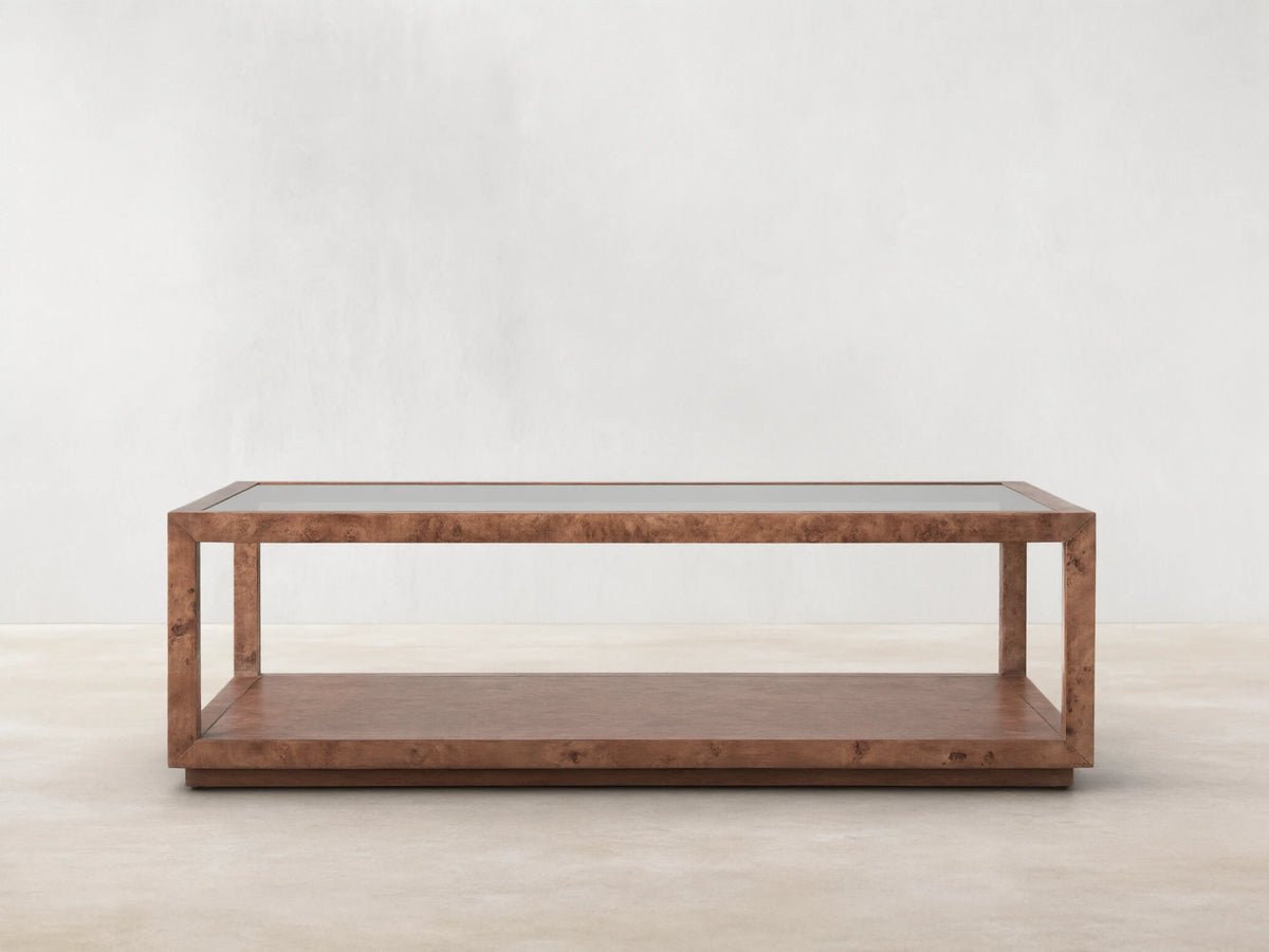 Corey Coffee Table with a rectangular shape, mappa burl wood finish, and open design. It has a top and lower surface in a light brown room setting.