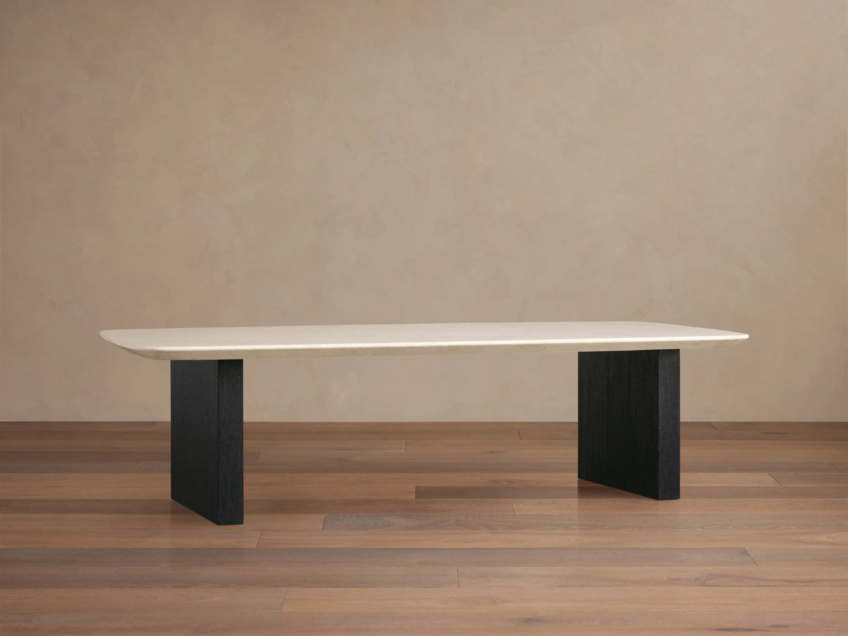Stone top coffee table with a creamy Carrara marble surface and flat edges. Supported by two rectangular ebony-finished wooden bases.
