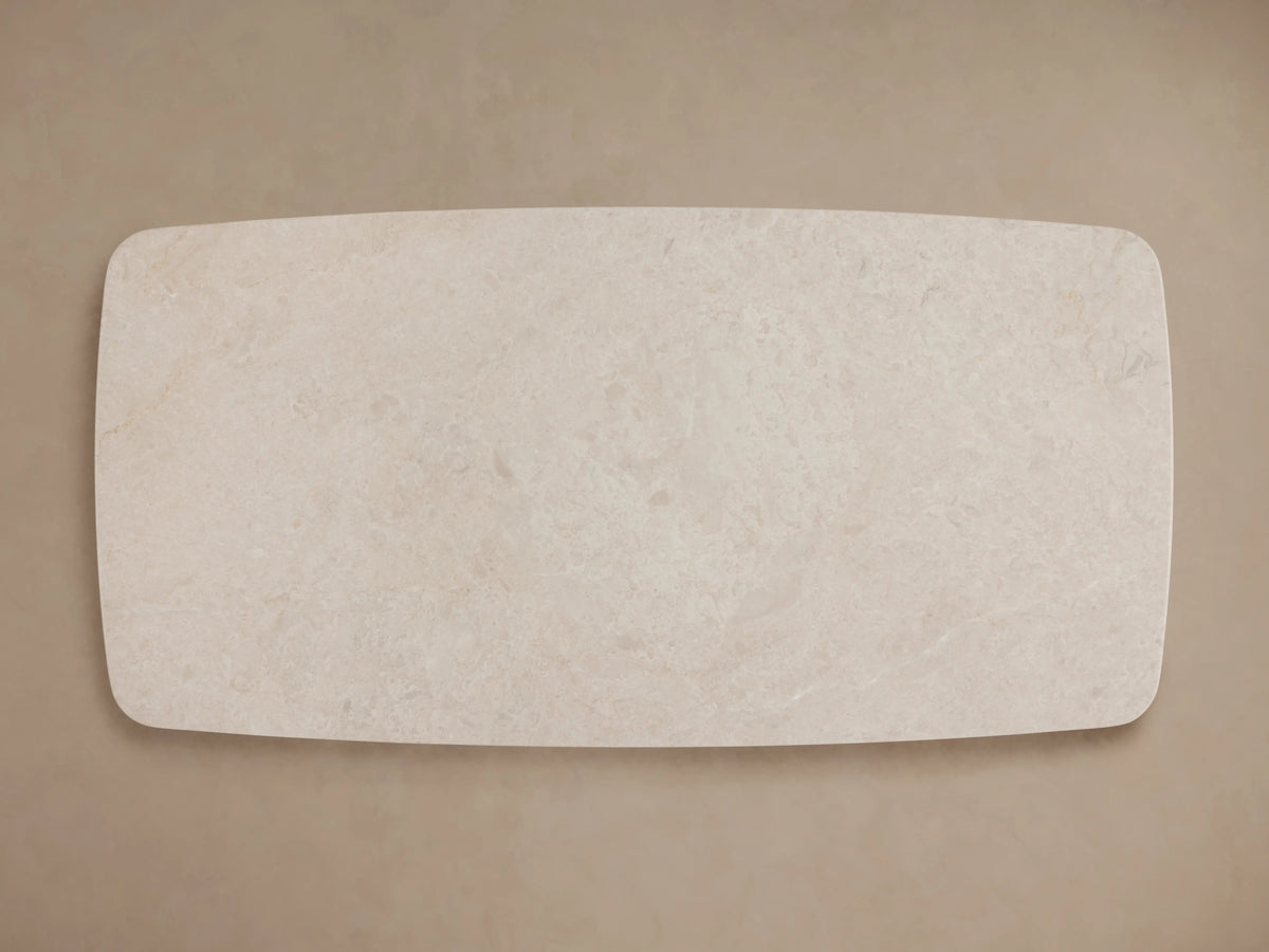Saint Germain Stone Coffee Table with cream marble top and two dark wooden Dauphine bases on wood floor, beige wall.