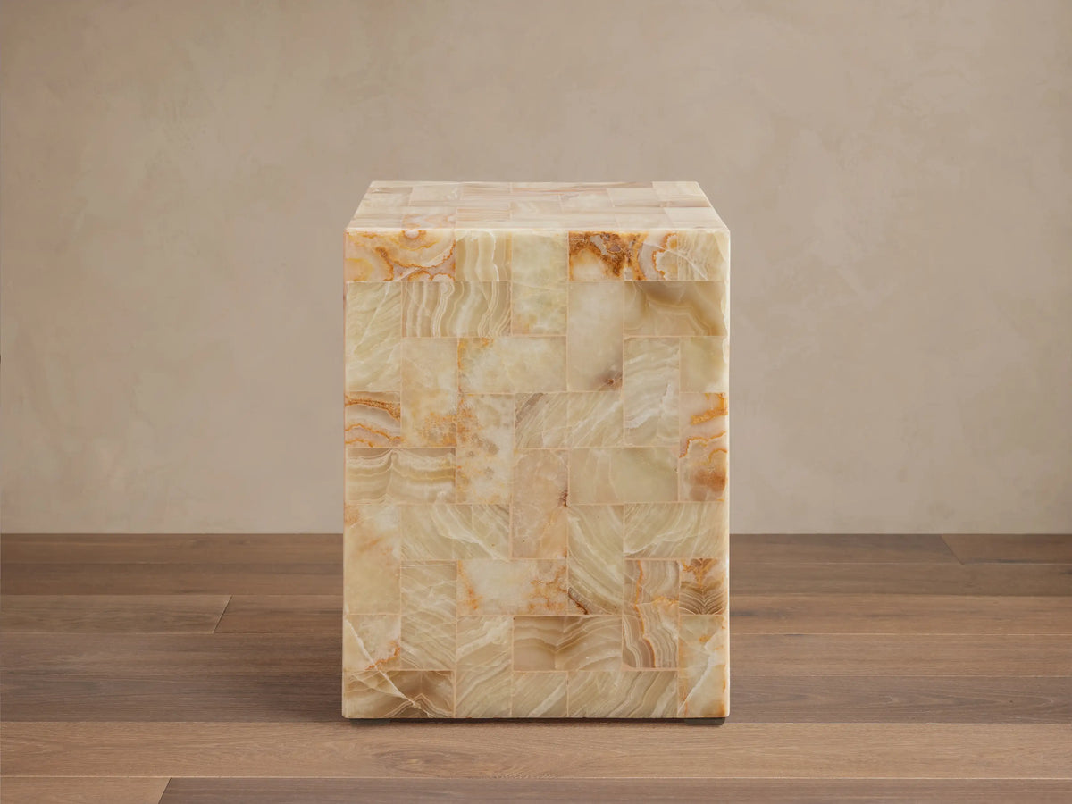 Dasha Onyx Stool with square shape, featuring a tiled design in ivory, light green, and rust tones on a wooden floor.
