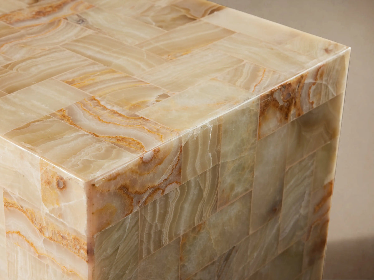 Square Dasha Onyx Stool with a tiled design of ivory, light green, and rust tones, placed on a wooden floor.