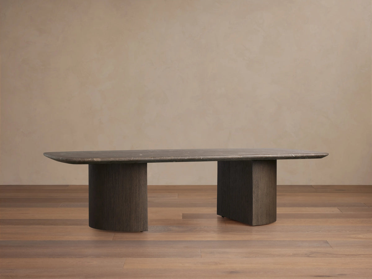 Saint Germain Coffee Table with marble top in neutral tones, featuring a rectangular surface and dual cylindrical wooden bases on a wood floor.
