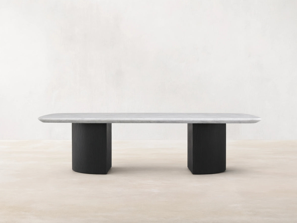 Saint Germain Stone Coffee Table with a long, oval Carrara marble top, cream color, on two solid, rectangular, dark ebony bases.