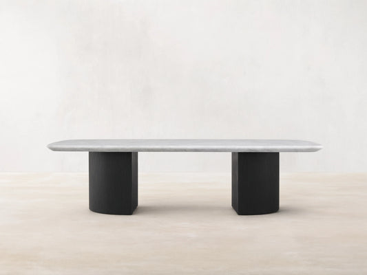 Saint Germain Stone Coffee Table with a long, oval Carrara marble top, cream color, on two solid, rectangular, dark ebony bases.