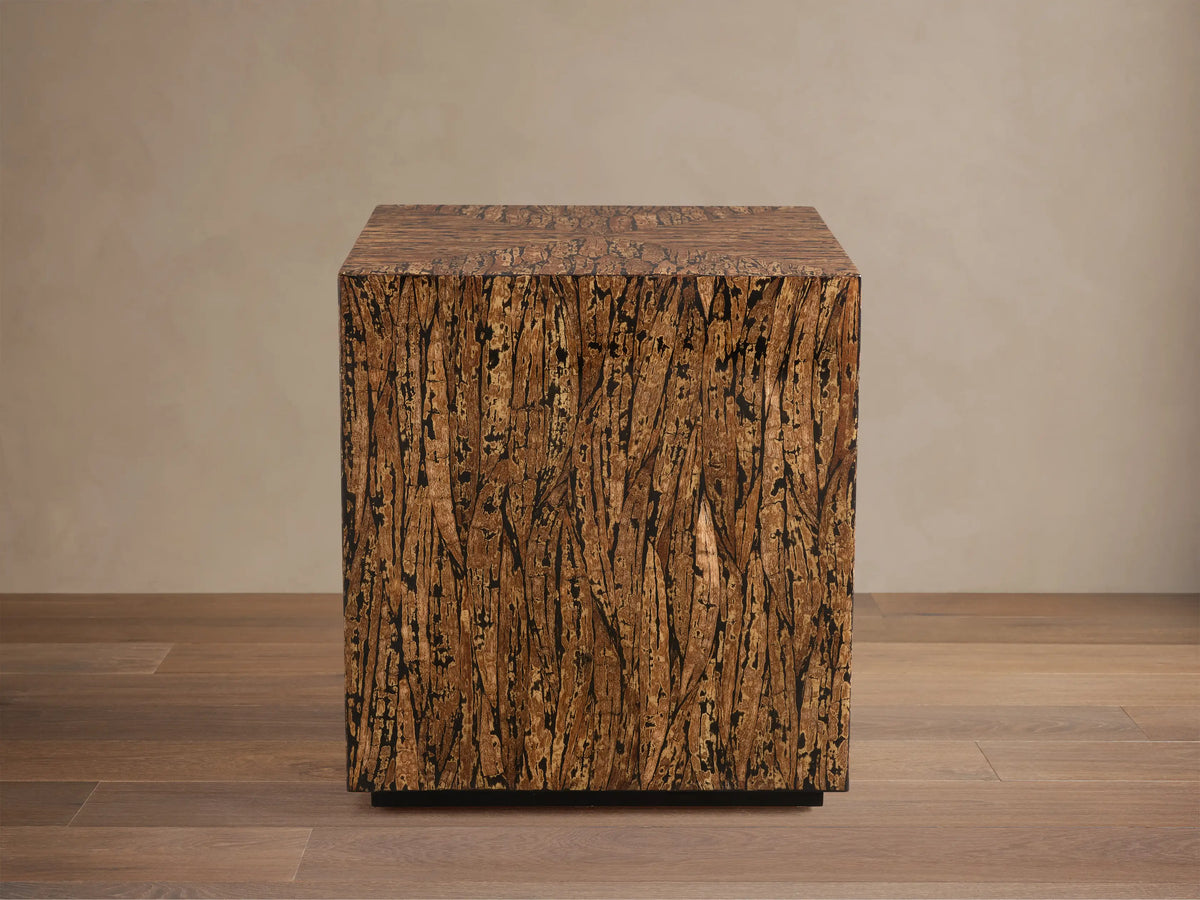 Desi End Table: cube-shaped, natural kapok wood veneer with marbled brown grain and distinct black resin accents.