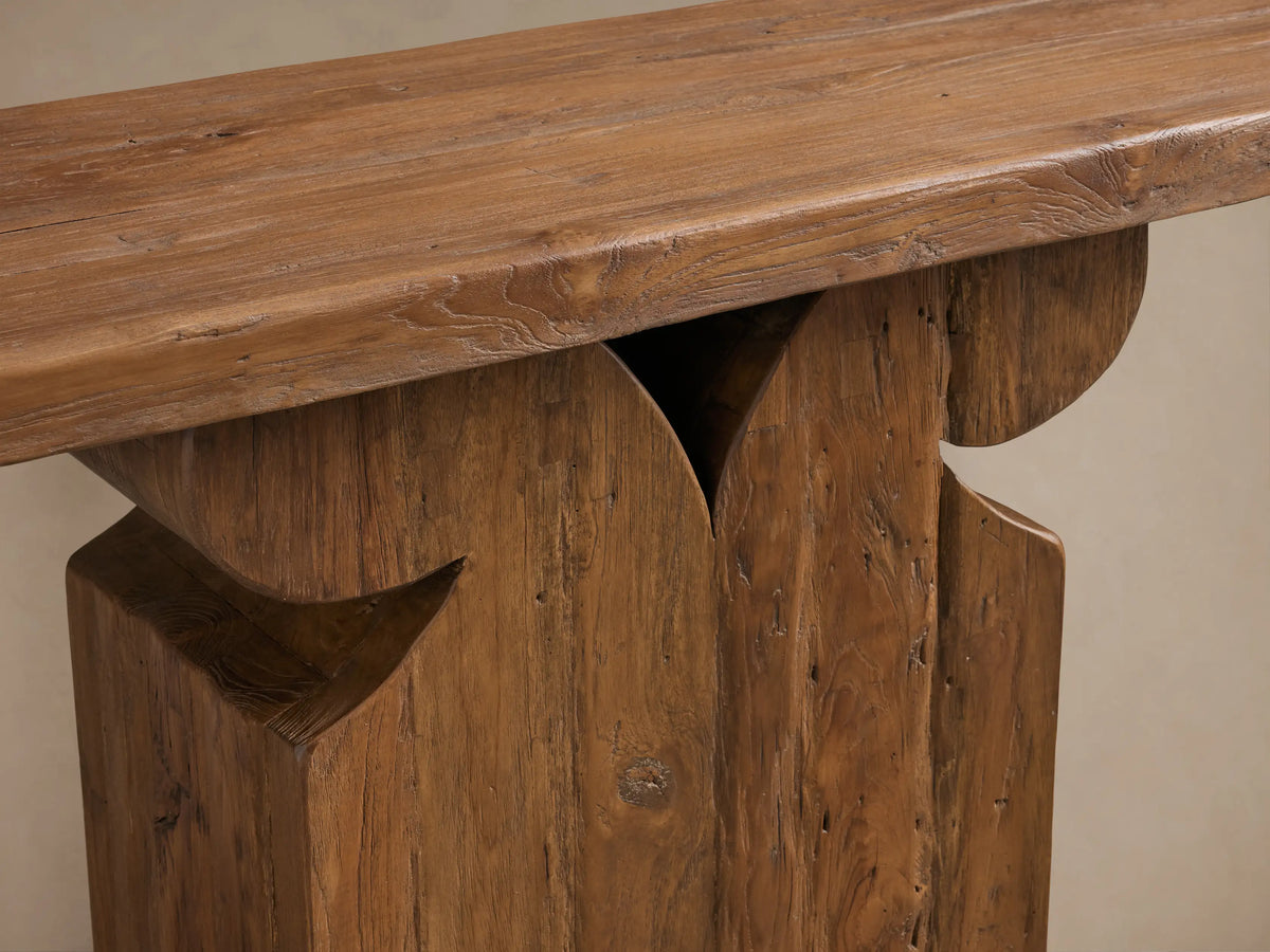 Dumai Console Table in natural wood finish, featuring a sleek rectangular top and a uniquely carved geometric base design.