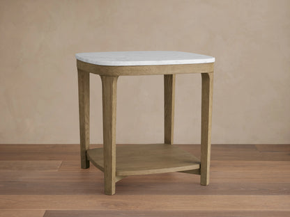 Danny End Table with an ivory-toned marble top and oak wood frame. Elegant square design with a lower shelf, set against a neutral wall.