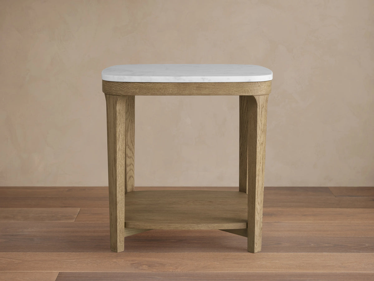 Danny End Table with a white marble top and oak wood frame in fawn finish, features a lower wooden shelf on a wooden floor.