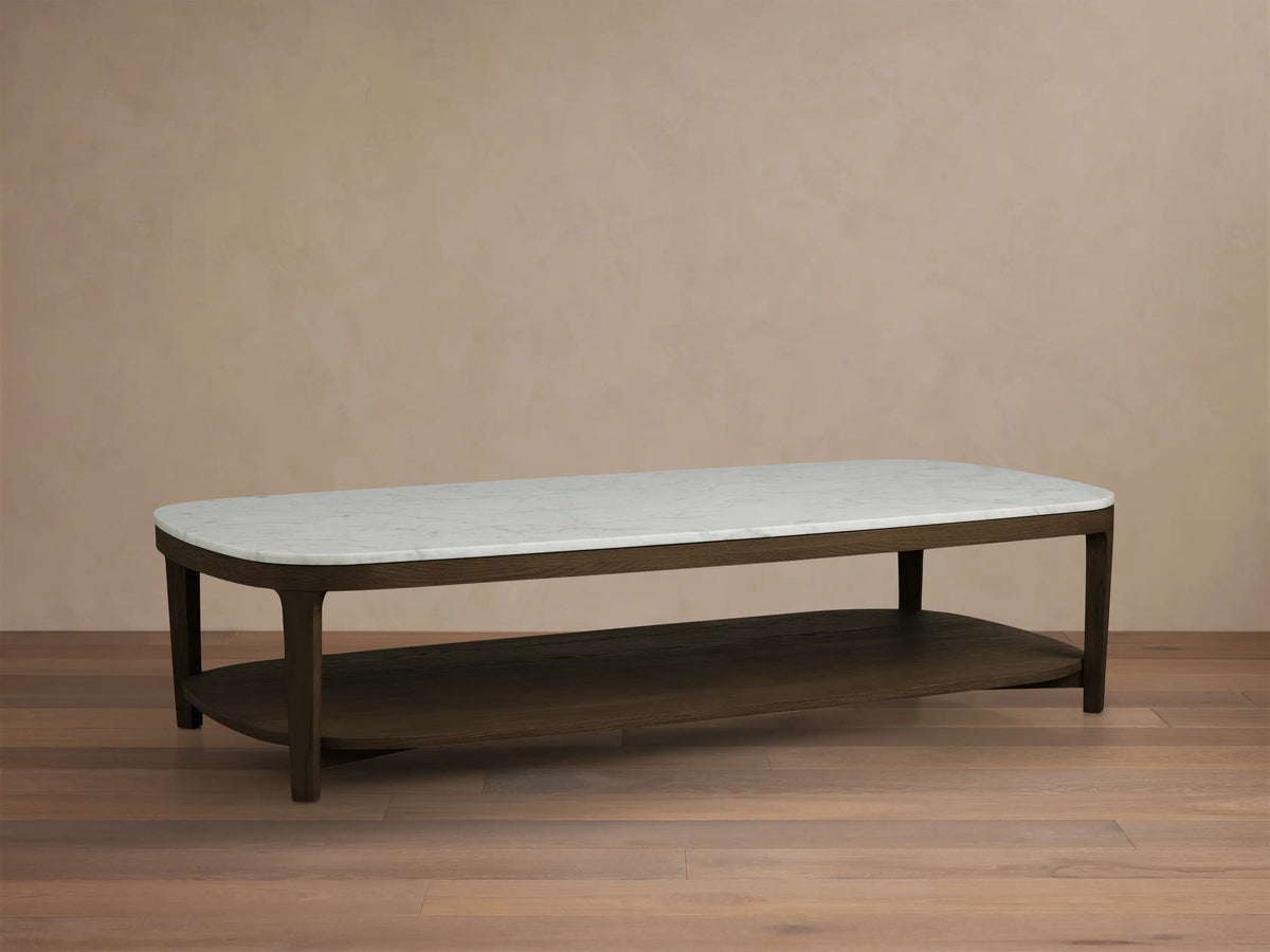 Front view of an oval coffee table with a white marble top and a dark brown wood frame and lower shelf.