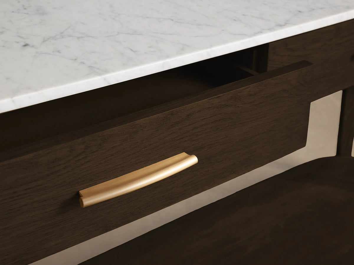 Close-up of a dark brown wooden vanity with a white marble top, showing an open drawer with a curved gold pull handle.