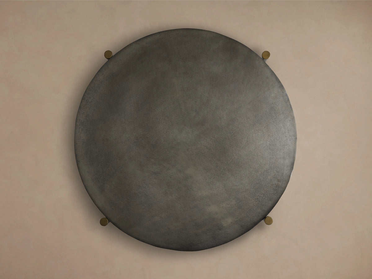 Round Donovan Coffee Table with a textured dark surface in black nickel, viewed from above. Four small brass accents at the edges.