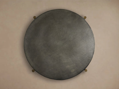 Round Donovan Coffee Table with a textured dark surface in black nickel, viewed from above. Four small brass accents at the edges.