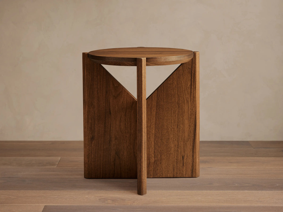 Elien End Table with round top in walnut veneer, featuring knife-edge detailing. Triangular legs create a geometric design.