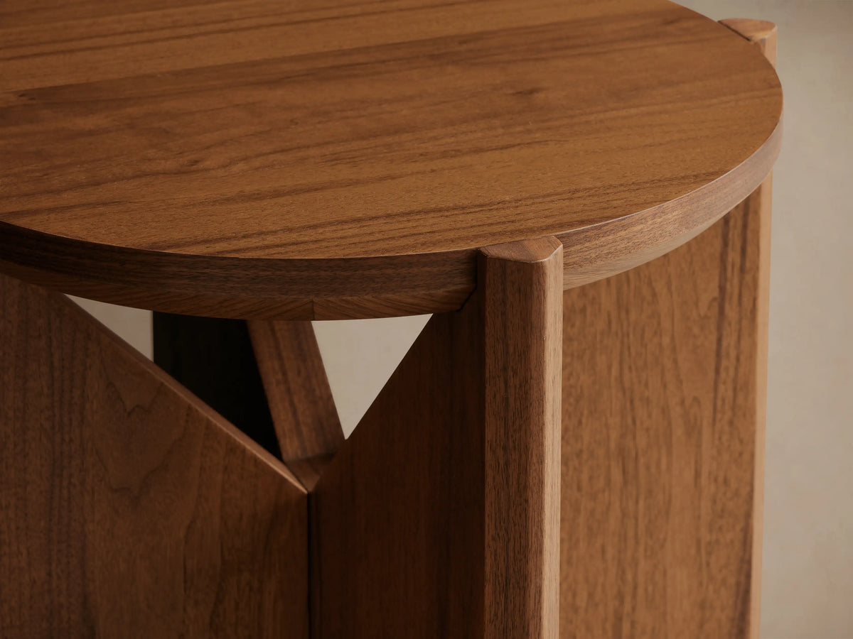 Elien End Table with round top and knife-edge detailing, crafted from walnut veneers. Wooden base with triangular support design.