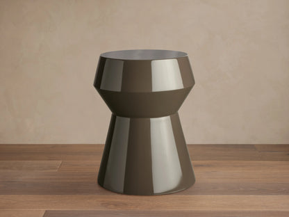 Eris Lacquer Stool in a brown high-gloss finish. Hourglass shape with a wide top and base, placed on a wooden floor.