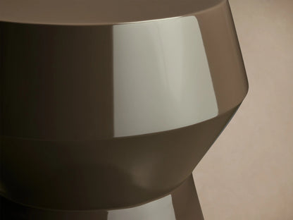 Eris Lacquer Stool in a brown high-gloss finish. Hourglass shape with a wide top and base, placed on a wooden floor.