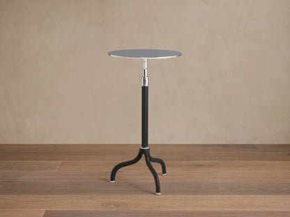 Ferdinand Leather Martini Table on a wooden floor, featuring a slender black tripod base and round brass-finished tabletop.