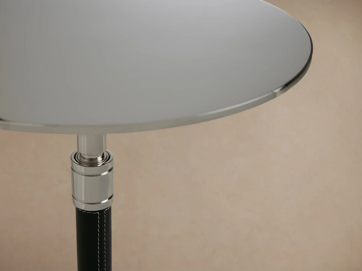 Ferdinand Leather Martini Table on a wooden floor, featuring a slender black tripod base and round brass-finished tabletop.