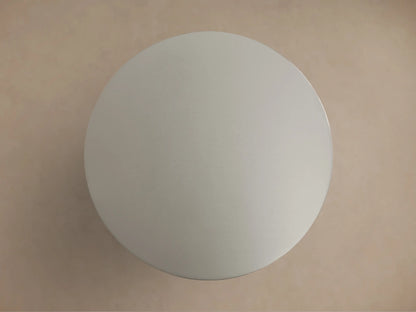 Ferdinand Martini Table with a sleek, round metallic top and sturdy cylindrical base shown against a beige background.