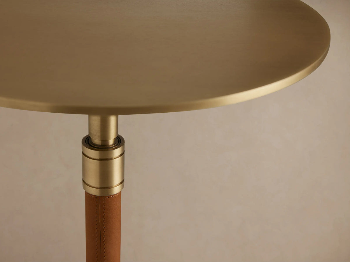 Ferdinand Leather Martini Table with a round brass-finished tabletop, olive leather-wrapped stem, and tripod base on wood floor.