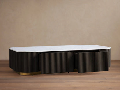 Finnley Storage Coffee Table with a white top and dark ribbed sides on a brass-finished base, on a wooden floor.