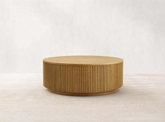 Finnley Round Wood Coffee Table in Honey finish, featuring a circular shape with vertical slats, placed on wooden flooring.