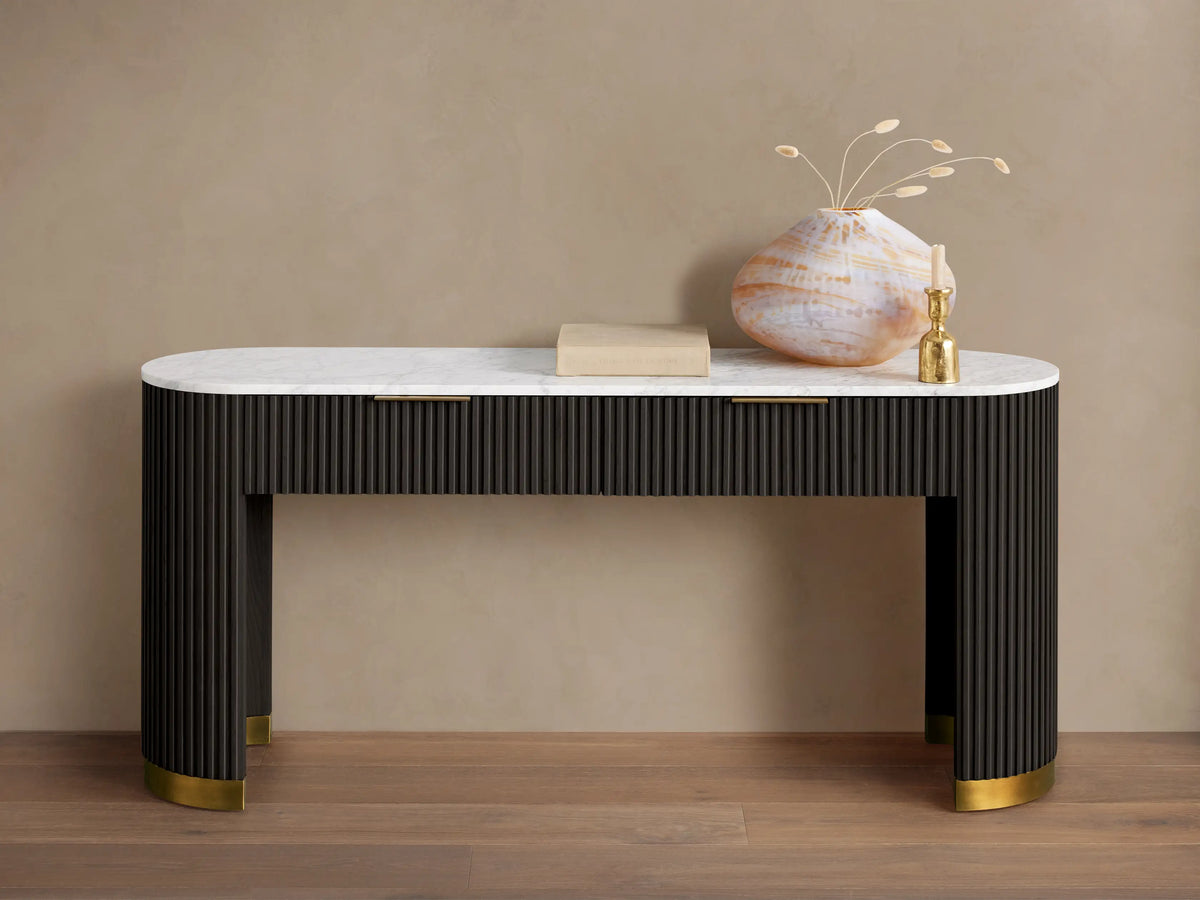 Finnley Storage Console Table in dark wood with brass plinth base, featuring a white top, a book, vase, and sculpture on it.