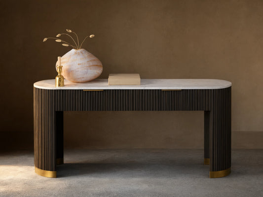 Finnley Storage Console Table in dark wood with brass plinth base, featuring a white top, a book, vase, and sculpture on it.