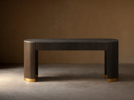 Finnley Console Table in dark wood with vertical ridges, brass-finished plinth bases, set on a wooden floor against a beige wall.